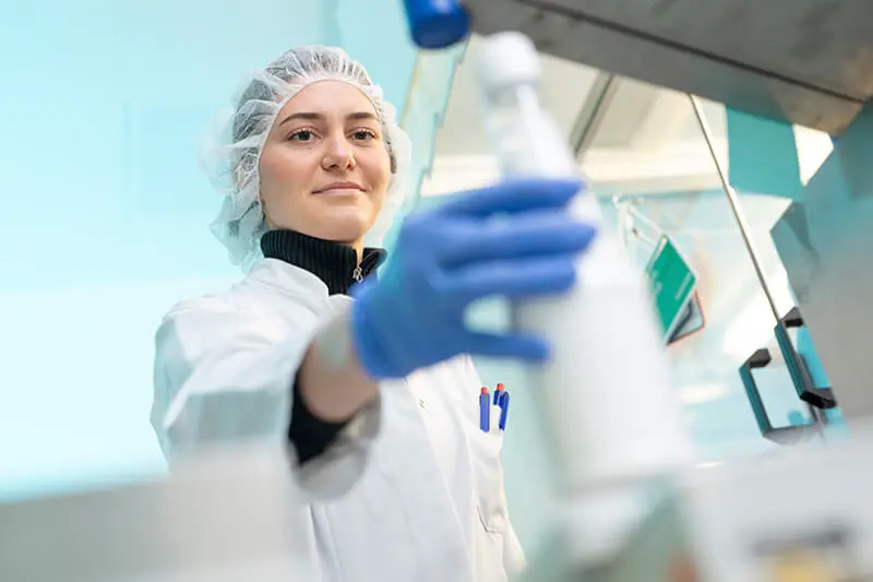 Frau hält Flasche mit weißer Flüssigkeit in der Hand