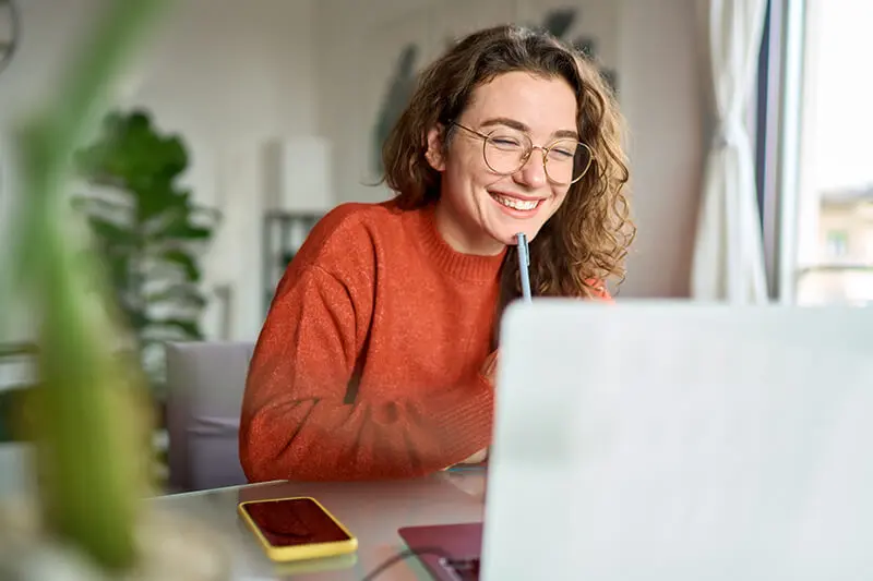 Frau schaut lächelnd in ihr Notebook