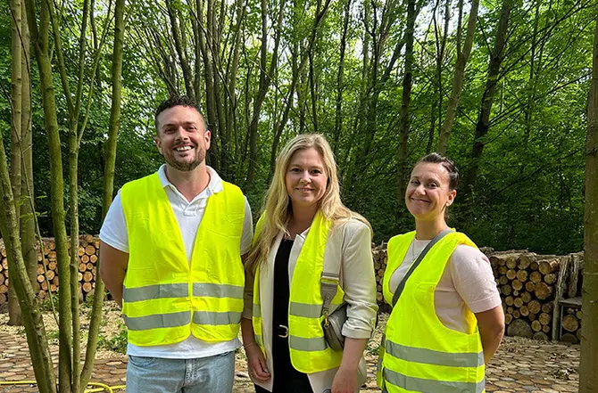 Drei Personen stehen mit Warnweste an einem Wald