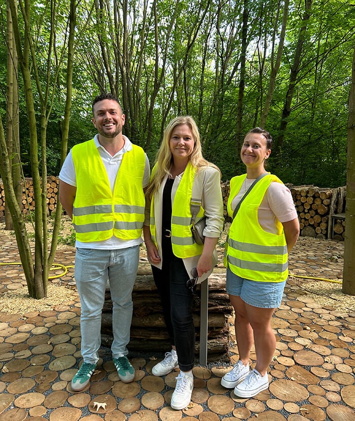 Drei Personen stehen mit Warnweste an einem Wald