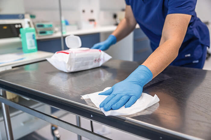 Person wischt Operationstisch mit Tuch